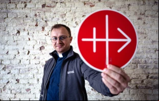 Un sacerdote sostiene el logo de Ayuda a la Iglesia Necesitada (ACN). Crédito: Ismael Martínez / ACN