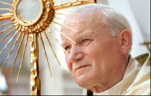 El Papa San Juan Pablo II sostiene una custodia durante la adoración eucarística. Fotografía tomada durante su visita apostólica a Polonia del 8 al 14 de junio de 1987. Crédito: Vatican Media